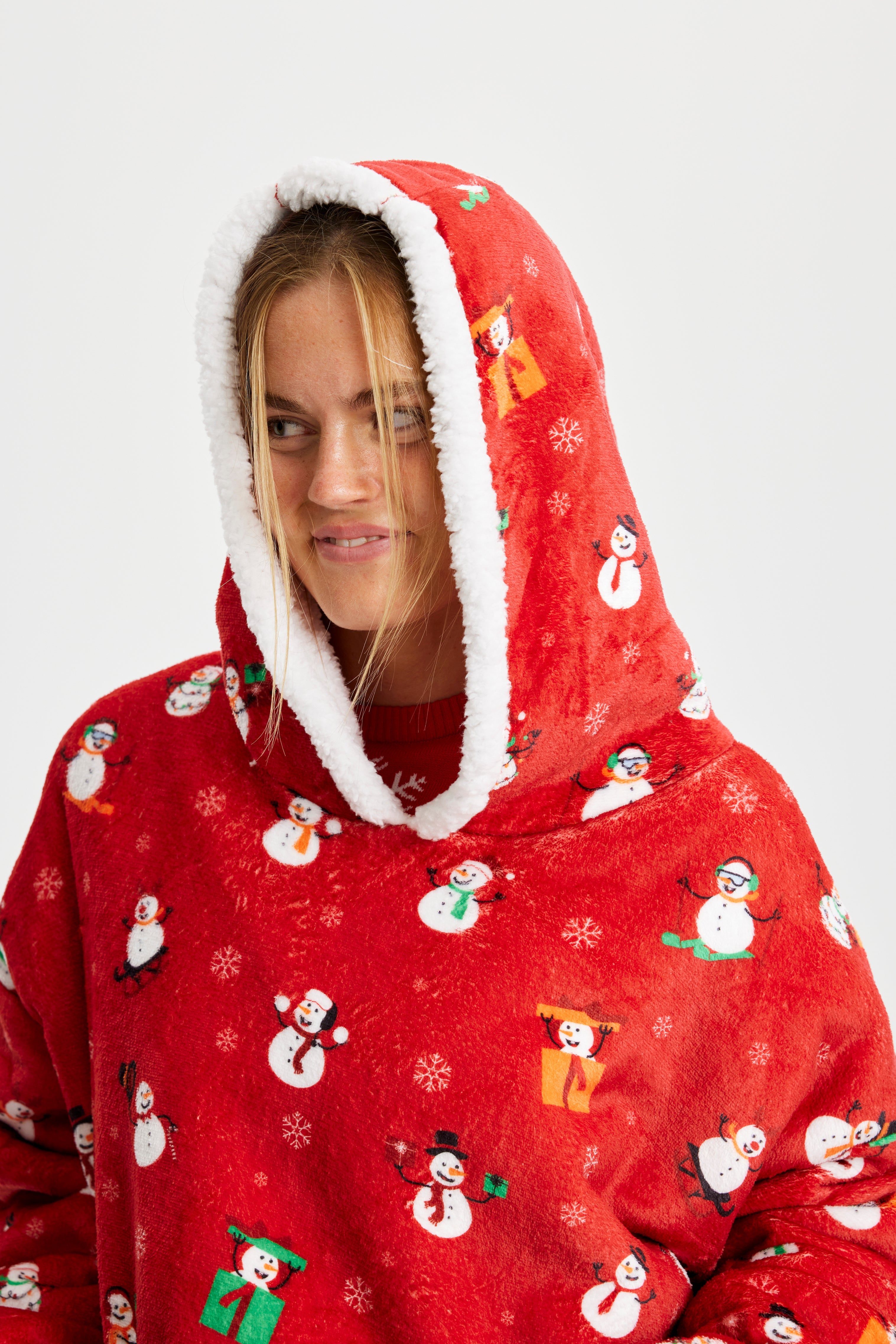 En kvinde kigger til siden med hætten trukket over hovedet, iført en fin julehoodie.